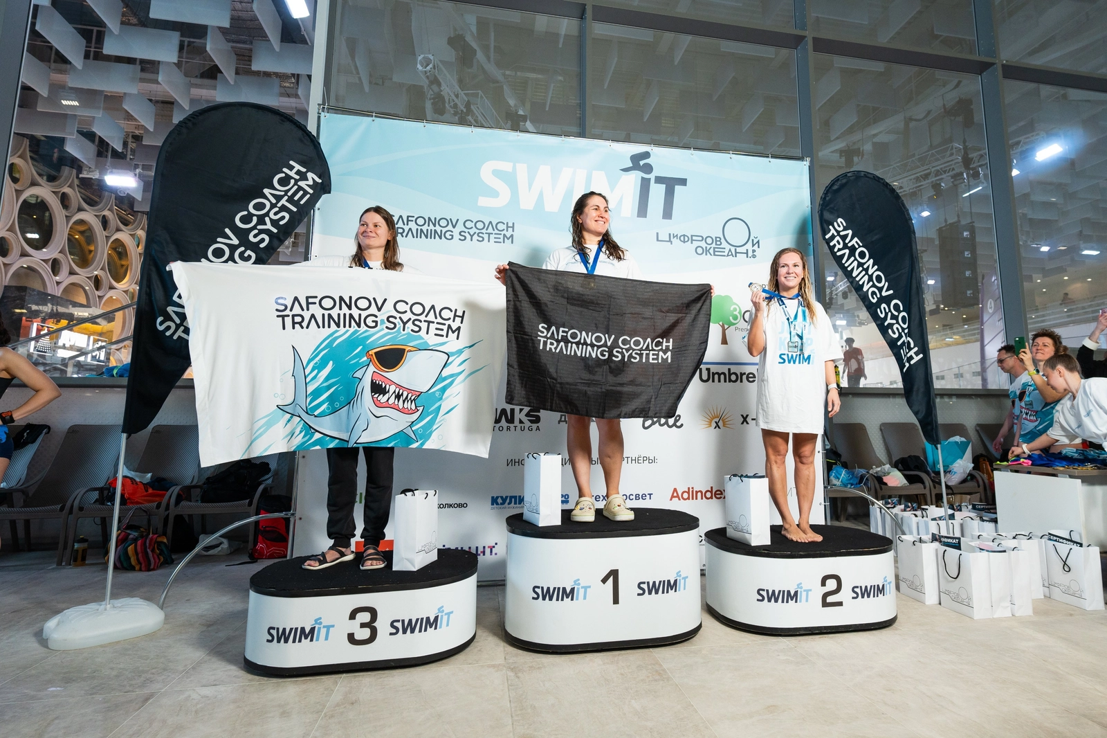 Три женщины стоят на призовом подиуме с медалями