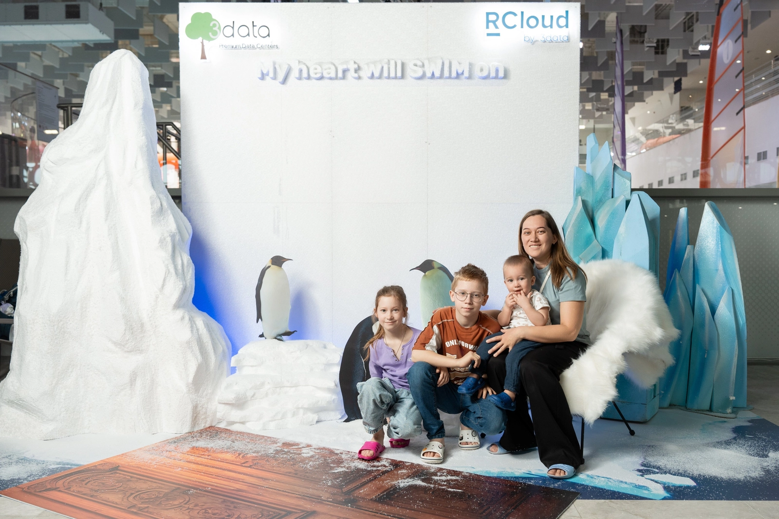 Мама с детьми на фоне декорации ледника с пингвинами