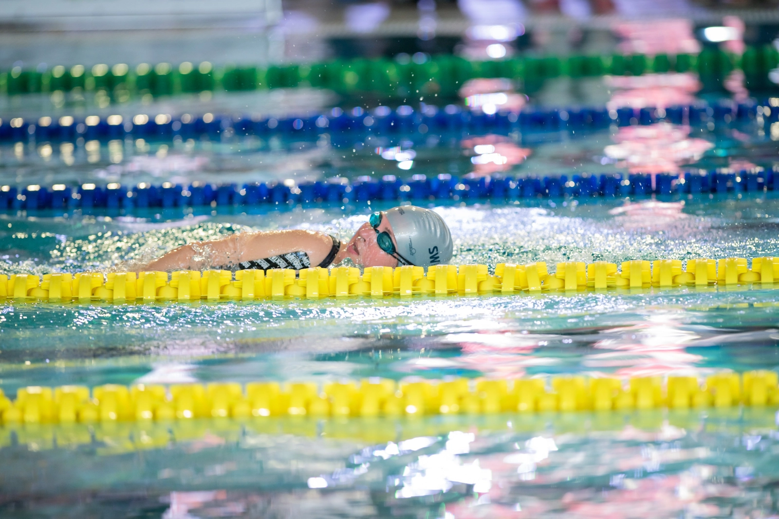 Пловчиха плывет по дорожке в бассейне