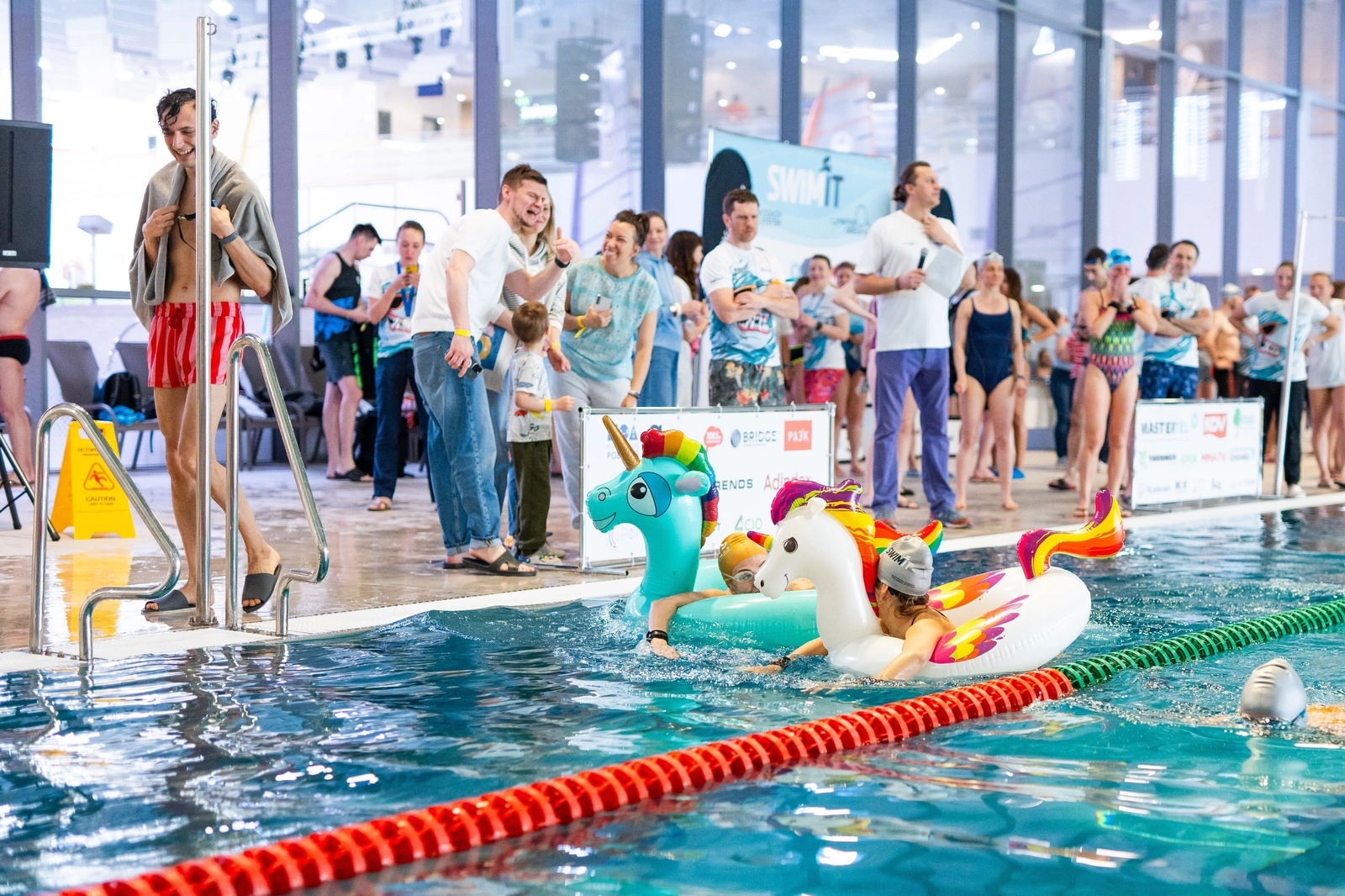 Две участницы плывут по дорожке с детскими надувными кругами