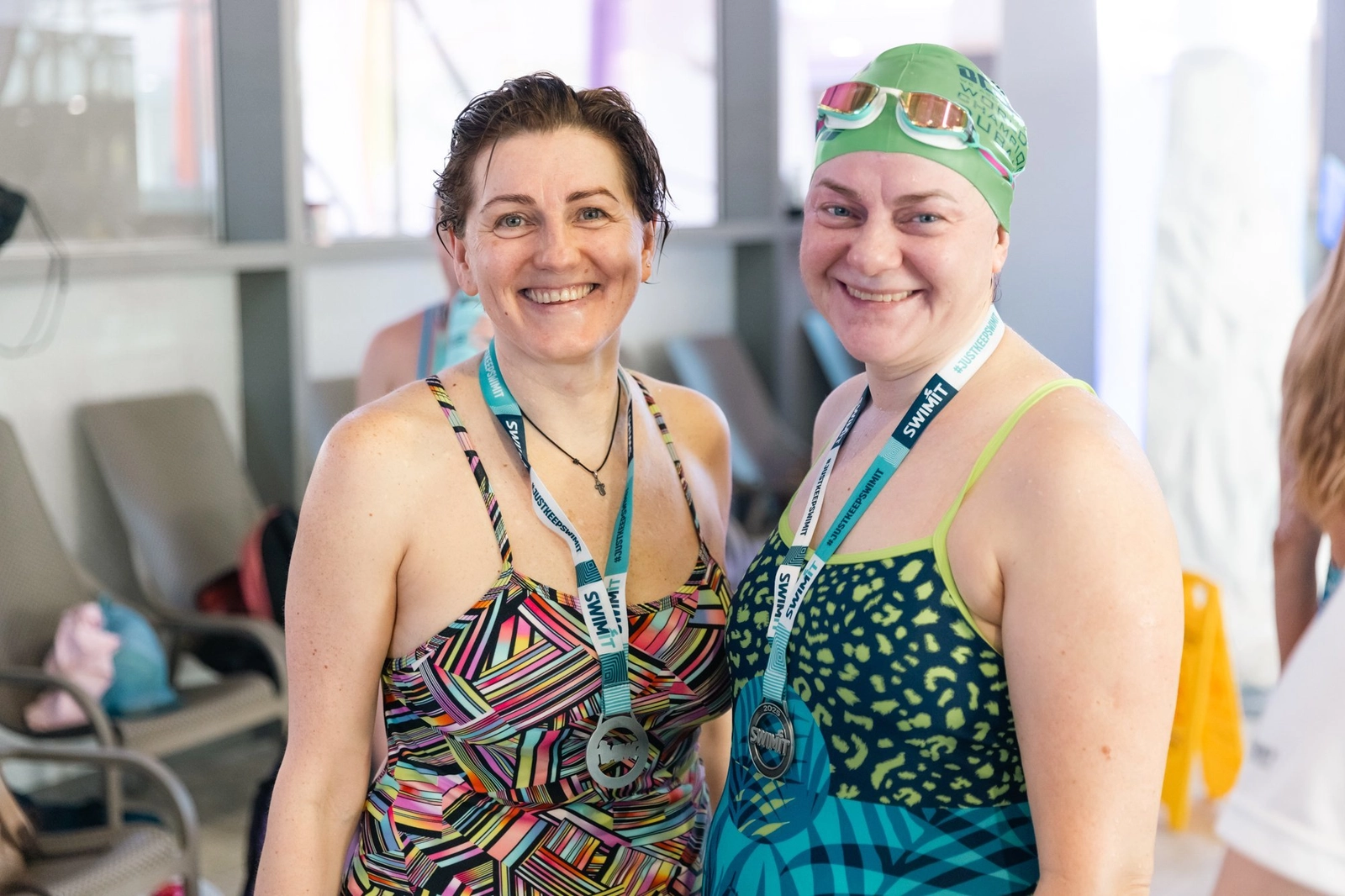 Две улыбающиеся женщины-пловчихи в купальниках с медалями на шее